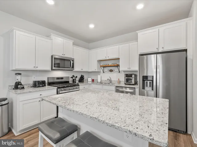 a kitchen with granite countertop a refrigerator stove top oven and sink