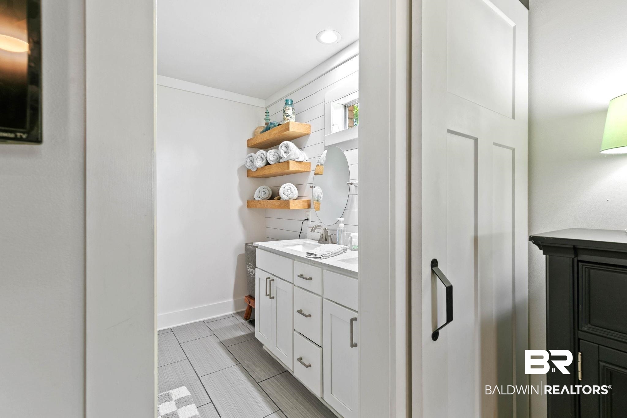 520 Juniper Place Drive Foley, AL 36535 - Photo 19 of 35 Bathroom featuring a white shaker vanity with a light-toned countertop, a rectangular undermount sink, and a wall-mounted circular mirror