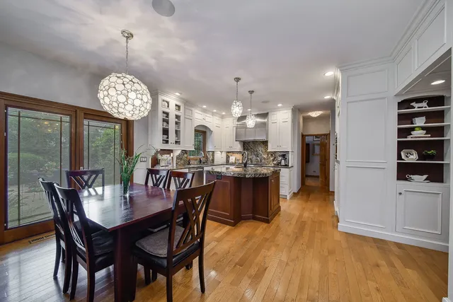 a view of a dining room and livingroom with furniture wooden floor a rug a chandelier and a mirror