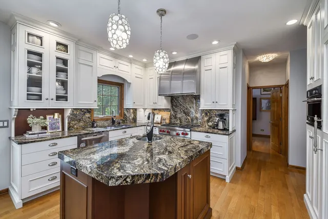 a kitchen with kitchen island granite countertop a center island a stove cabinets a dining table and chairs