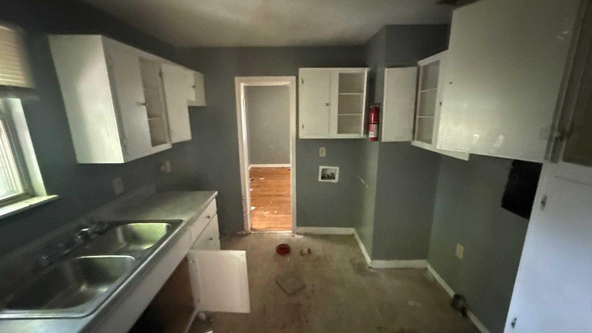 5425 Lochinvar Road Memphis, TN 38116 - Photo 6 of 9 Kitchen area with painted gray walls, white upper and lower cabinetry, a stainless steel double basin sink, and a window with blinds