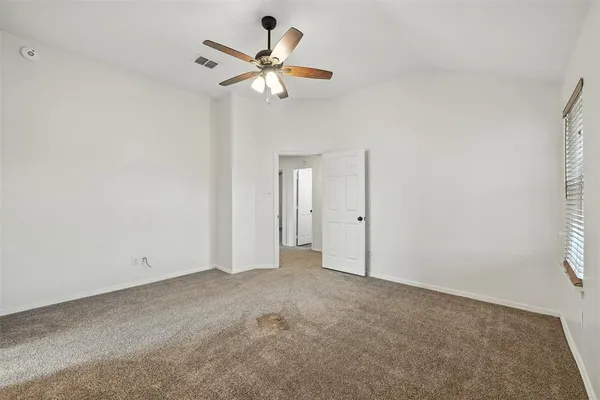 an empty room with a window and a fan