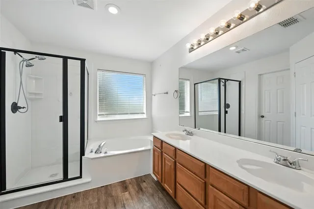 a bathroom with a double vanity sink a mirror and a bathtub
