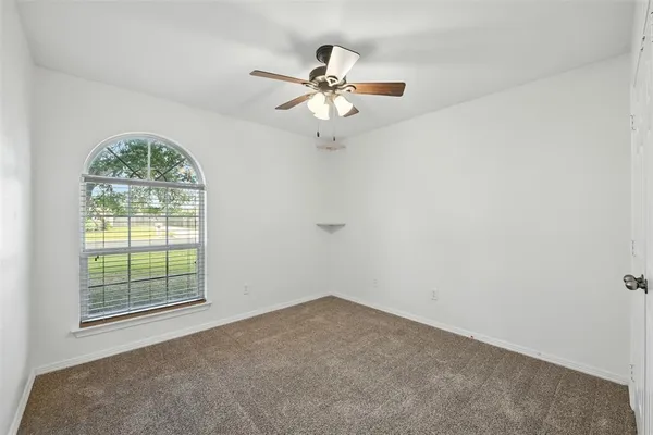 an empty room with a window and a fan
