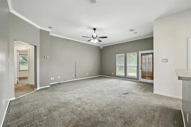 an empty room with chandelier fan and windows