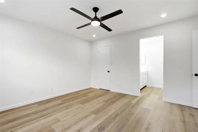 an empty room with wooden floor and ceiling fan