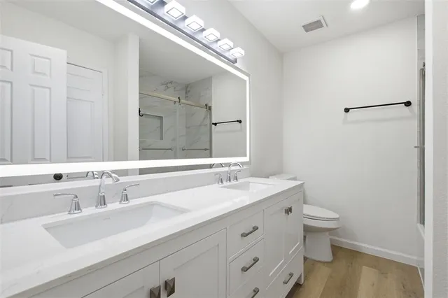 a bathroom with a double vanity sink toilet and a mirror