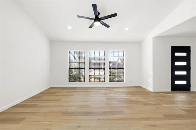 a view of an empty room with a window and wooden floor
