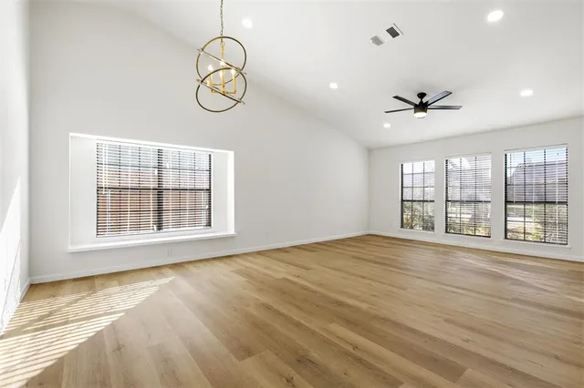 a view of an empty room with a window and wooden floor