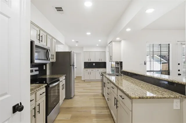 a large kitchen with stainless steel appliances granite countertop a sink stove and refrigerator