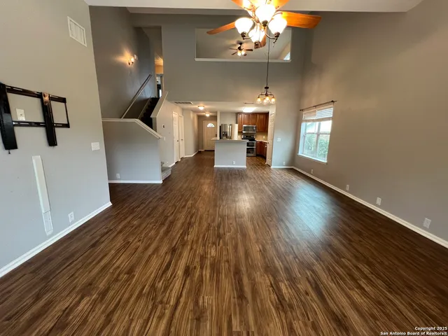 a view of an empty room with wooden floor and windows
