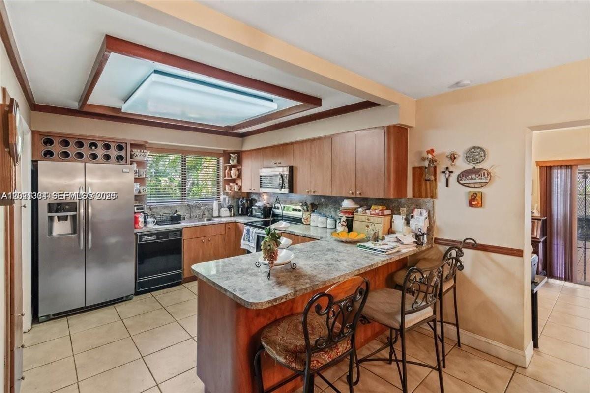 6385 Southwest 25th Street Miami, FL 33155 - Photo 6 of 28 a kitchen with stainless steel appliances granite countertop a table chairs and a refrigerator