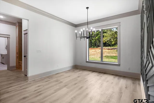 a view of an empty room with wooden floor kitchen view and a window
