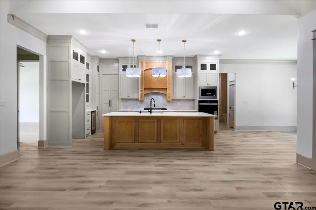 a large kitchen with stainless steel appliances kitchen island granite countertop a refrigerator and a stove top oven