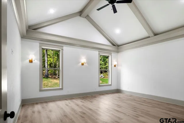 a view of an empty room with a window and wooden floor