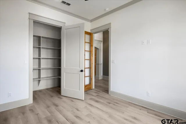 a view of an empty room with a closet and wooden shelves