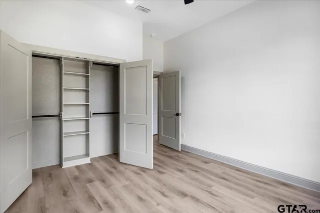 a view of empty room with wooden floor and closet