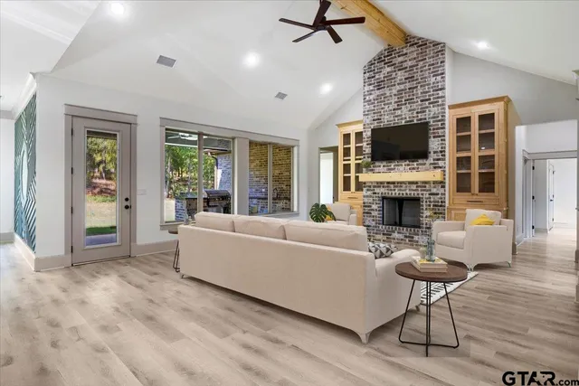 a living room with furniture a fireplace a flat screen tv and a window