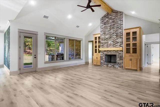 an empty room with windows fireplace and wooden floor