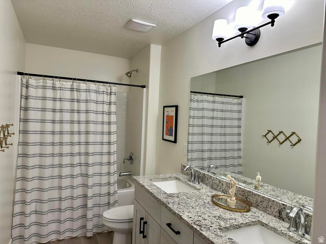 4349 Half Mile Road East Enoch, UT 84721 - Photo 30 of 36 Bathroom featuring double vanity, a textured ceiling, shower / bath combo with shower curtain, and dark wood finished floors