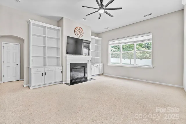 an empty room with windows fireplace and fans