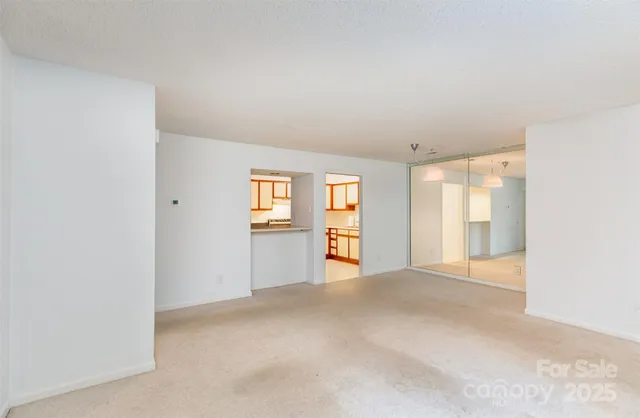a view of an empty room with window and wooden floor