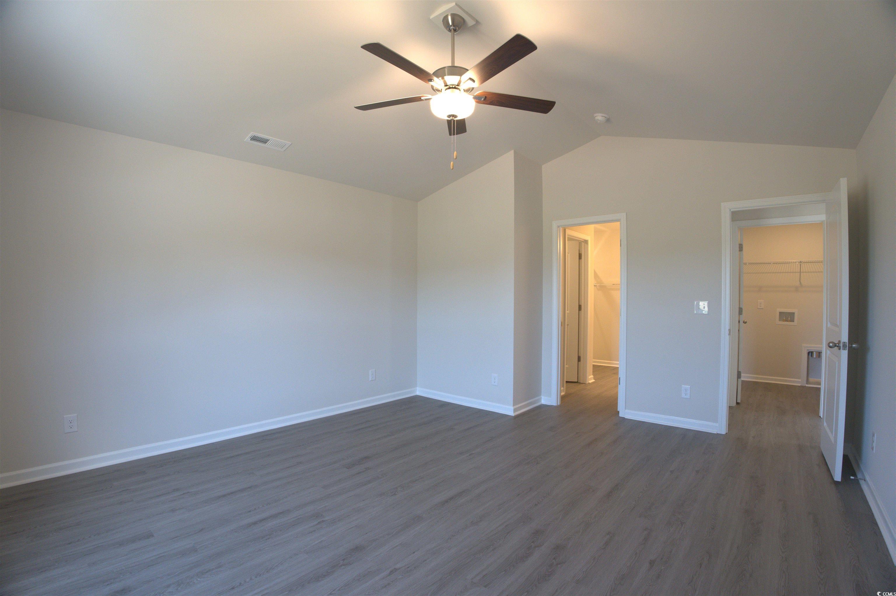 5721 Highway 41 Marion, SC 29571 - Photo 10 of 11 Unfurnished bedroom with vaulted ceiling, dark wood-style floors, a walk in closet, a ceiling fan, and a closet
