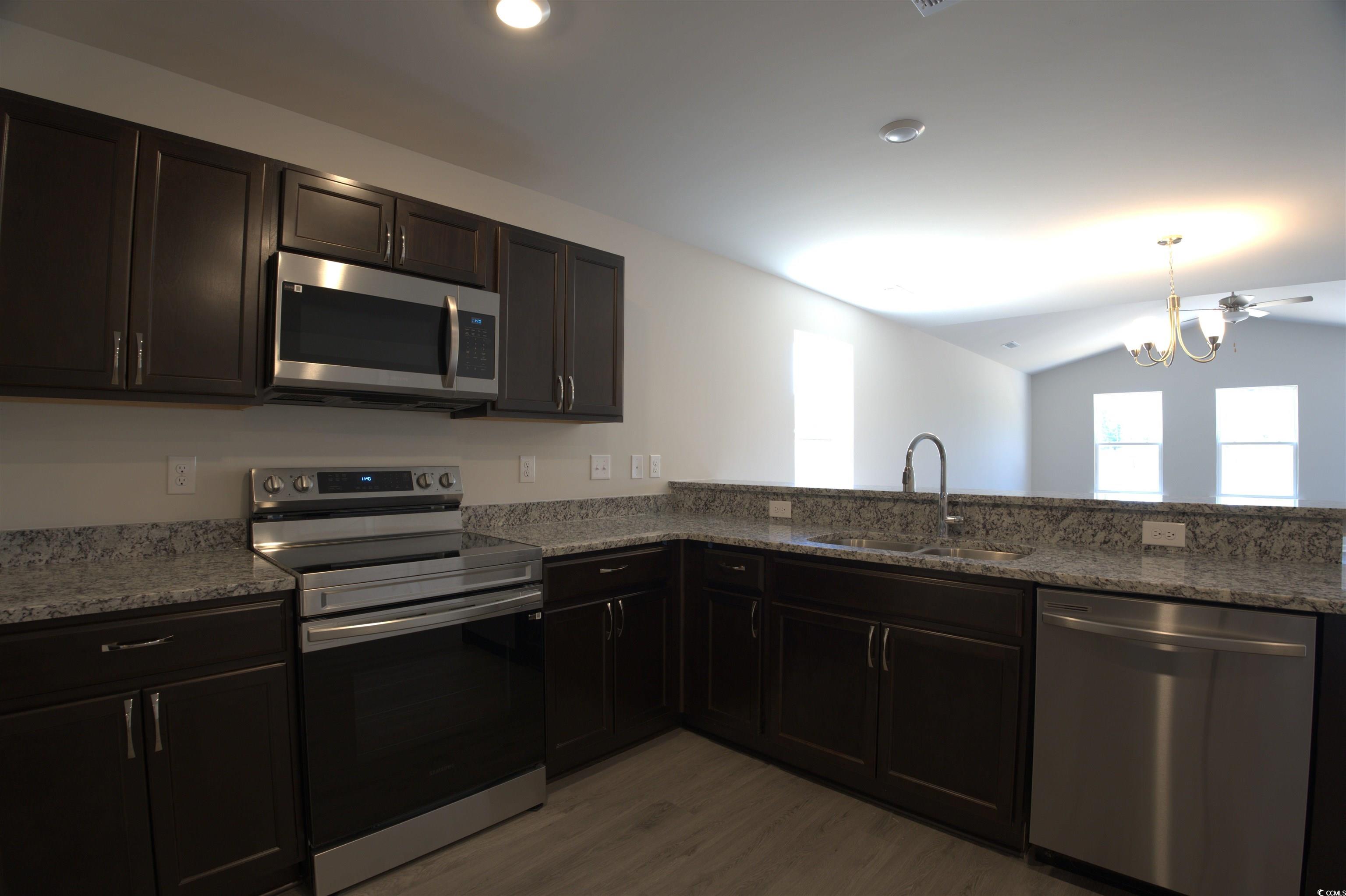 5721 Highway 41 Marion, SC 29571 - Photo 4 of 11 Kitchen with stainless steel appliances, light wood finished floors, light stone counters, lofted ceiling, and a chandelier
