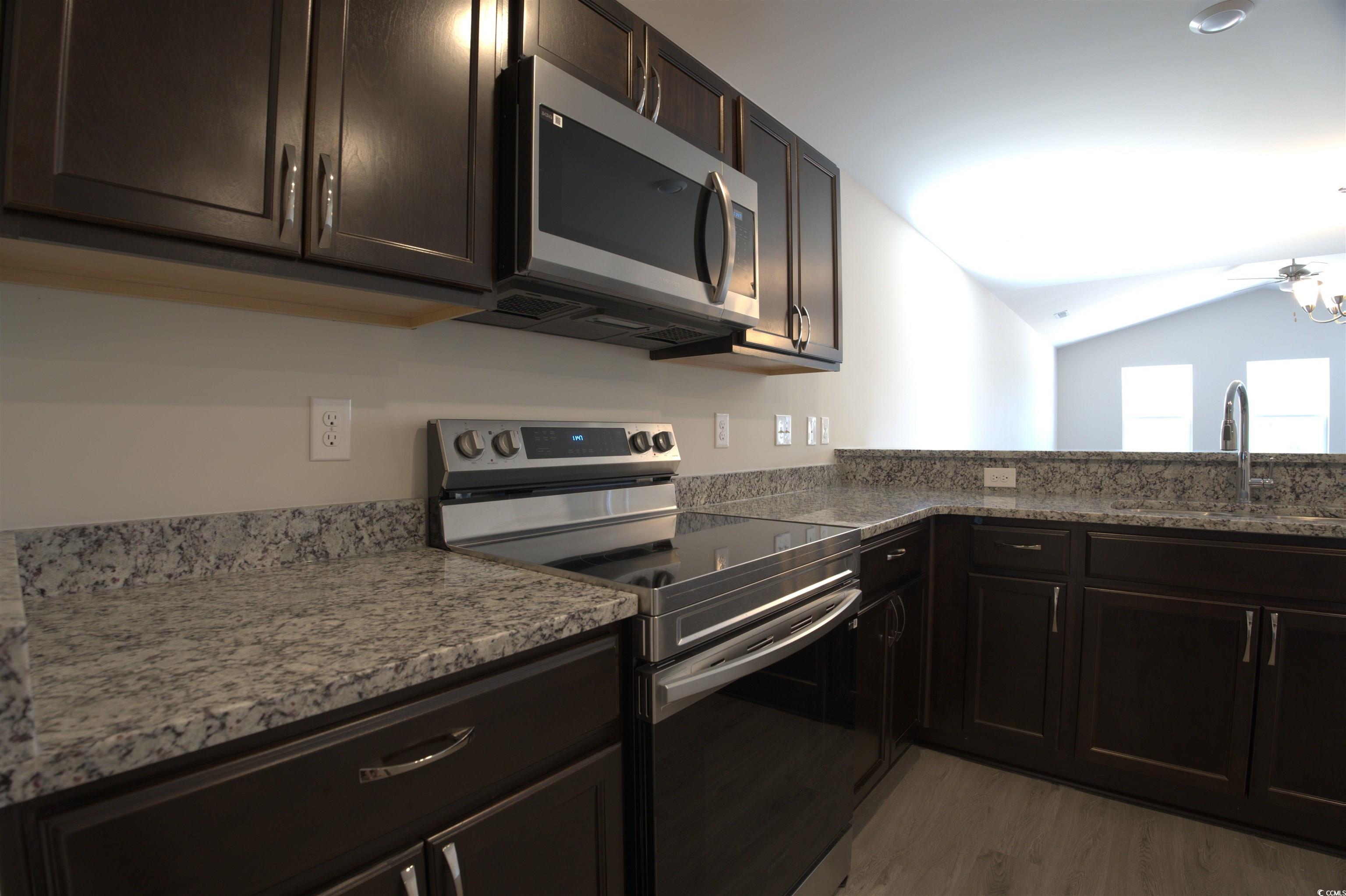 5721 Highway 41 Marion, SC 29571 - Photo 7 of 11 Kitchen featuring stainless steel appliances, light wood-style flooring, light stone counters, lofted ceiling, and dark brown cabinetry