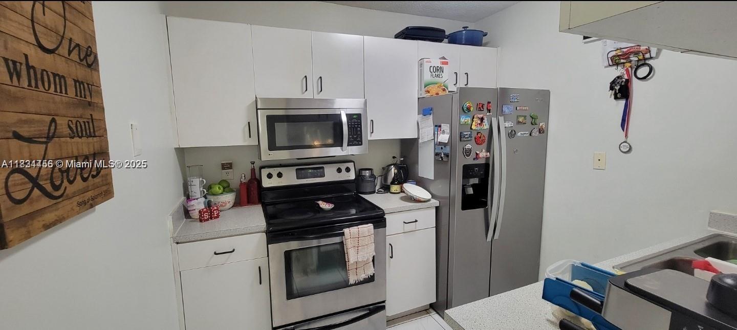 7121 Southwest 129th Avenue, Unit 5 Miami, FL 33183 - Photo 7 of 19 a kitchen with stainless steel appliances a stove a microwave and a refrigerator