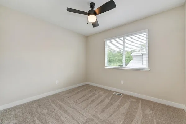 an empty room with a window and a fan
