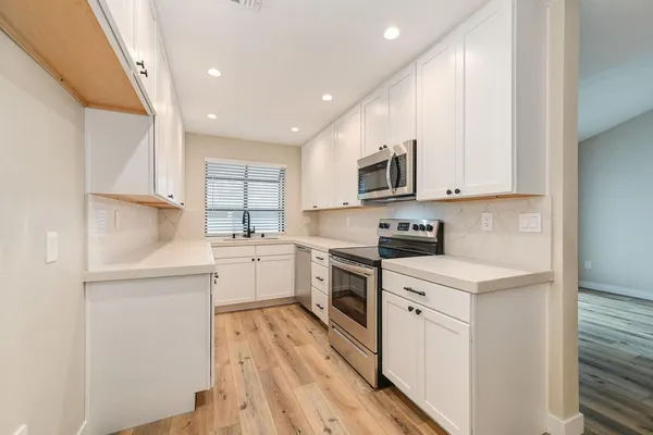 a kitchen with white cabinets appliances and sink