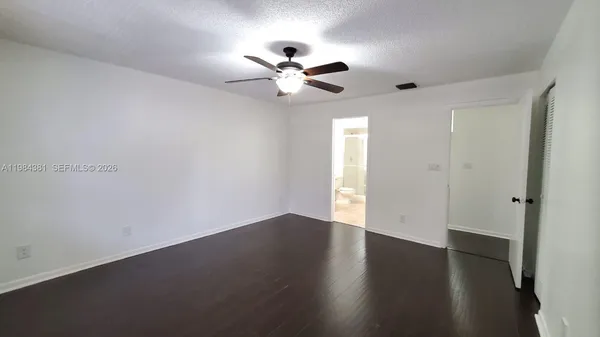 an empty room with wooden floor fan and windows