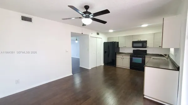 a kitchen with stainless steel appliances granite countertop a refrigerator a stove a microwave oven a sink with wooden floor
