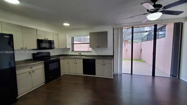 a kitchen with granite countertop a stove top oven a sink dishwasher a dining table and chairs with wooden floor