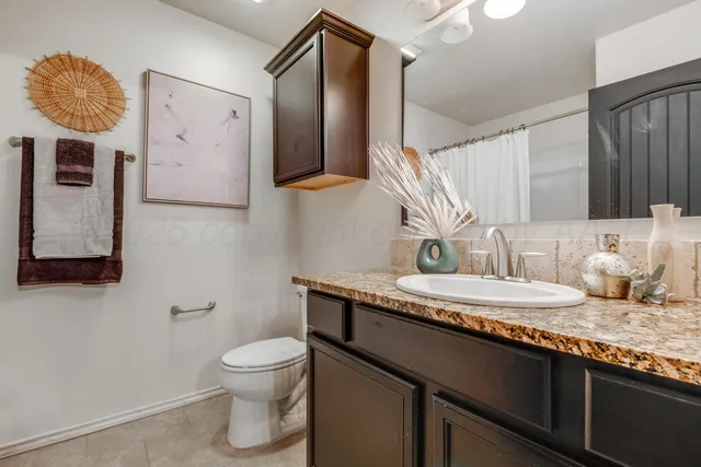 a bathroom with a granite countertop toilet sink and mirror