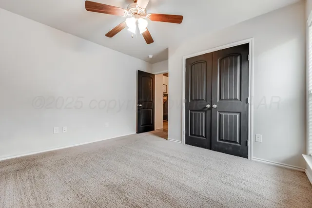 an empty room with closet and a chandelier fan