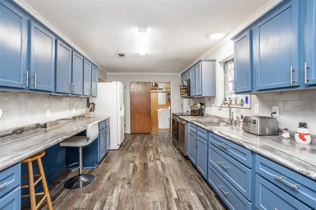 a kitchen with granite countertop wooden floors wooden cabinets and stainless steel appliances