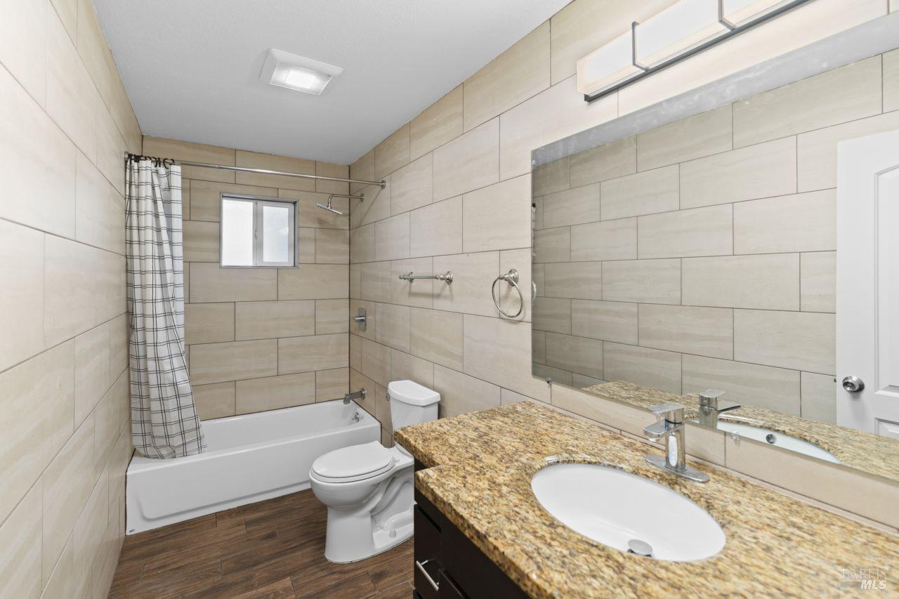 940 York Street Vallejo, CA 94590 - Photo 25 of 30 a bathroom with a granite countertop toilet a sink and bathtub