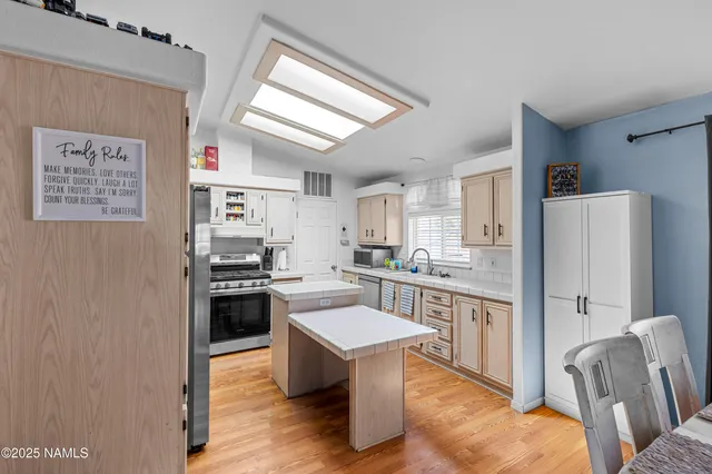 a kitchen with stainless steel appliances granite countertop a refrigerator a stove a sink dishwasher and white cabinets with wooden floor