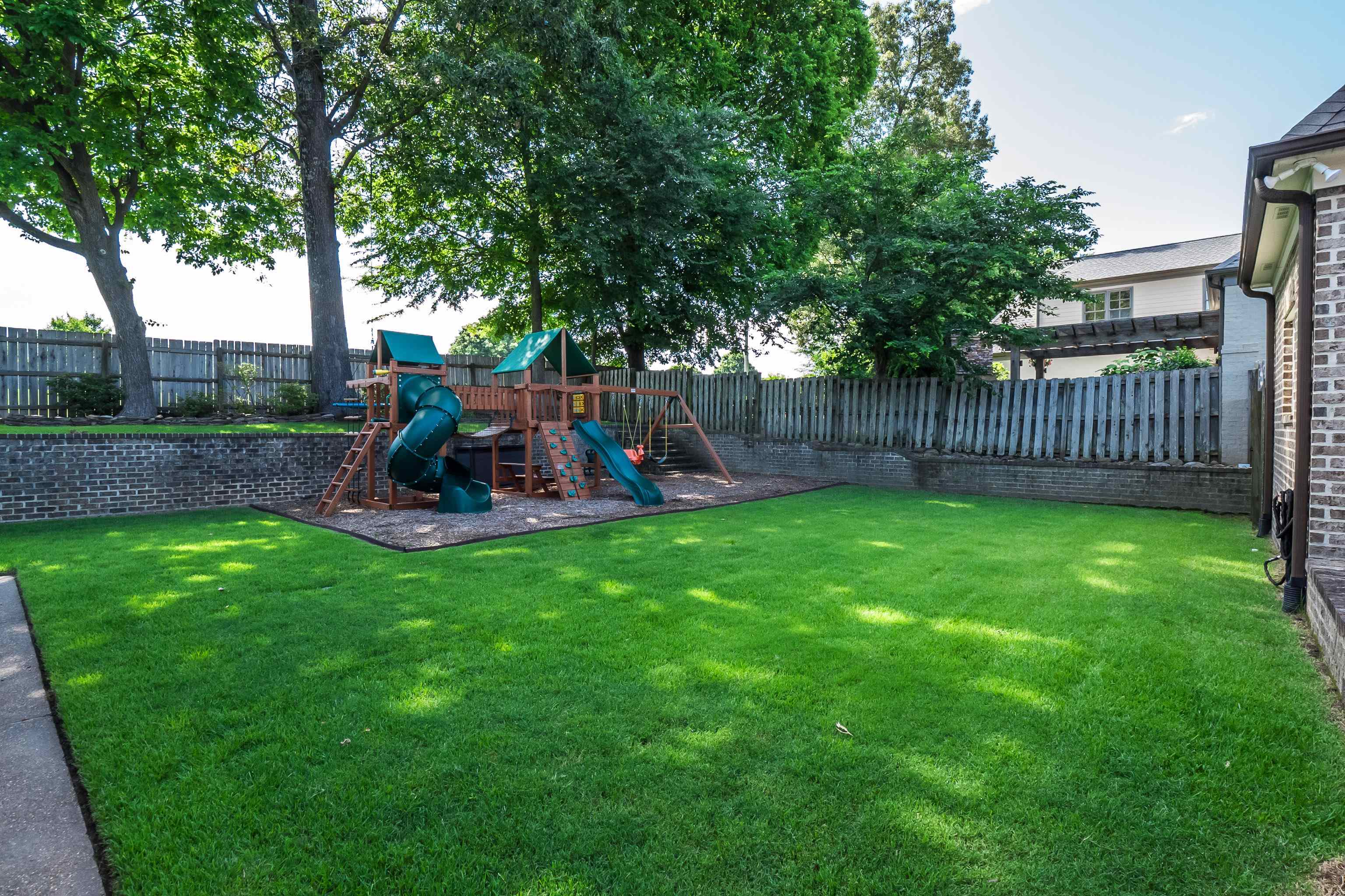 3174 Wetherby Drive Germantown, TN 38139 - Photo 36 of 40 a view of a backyard with a slide trees and wooden fence