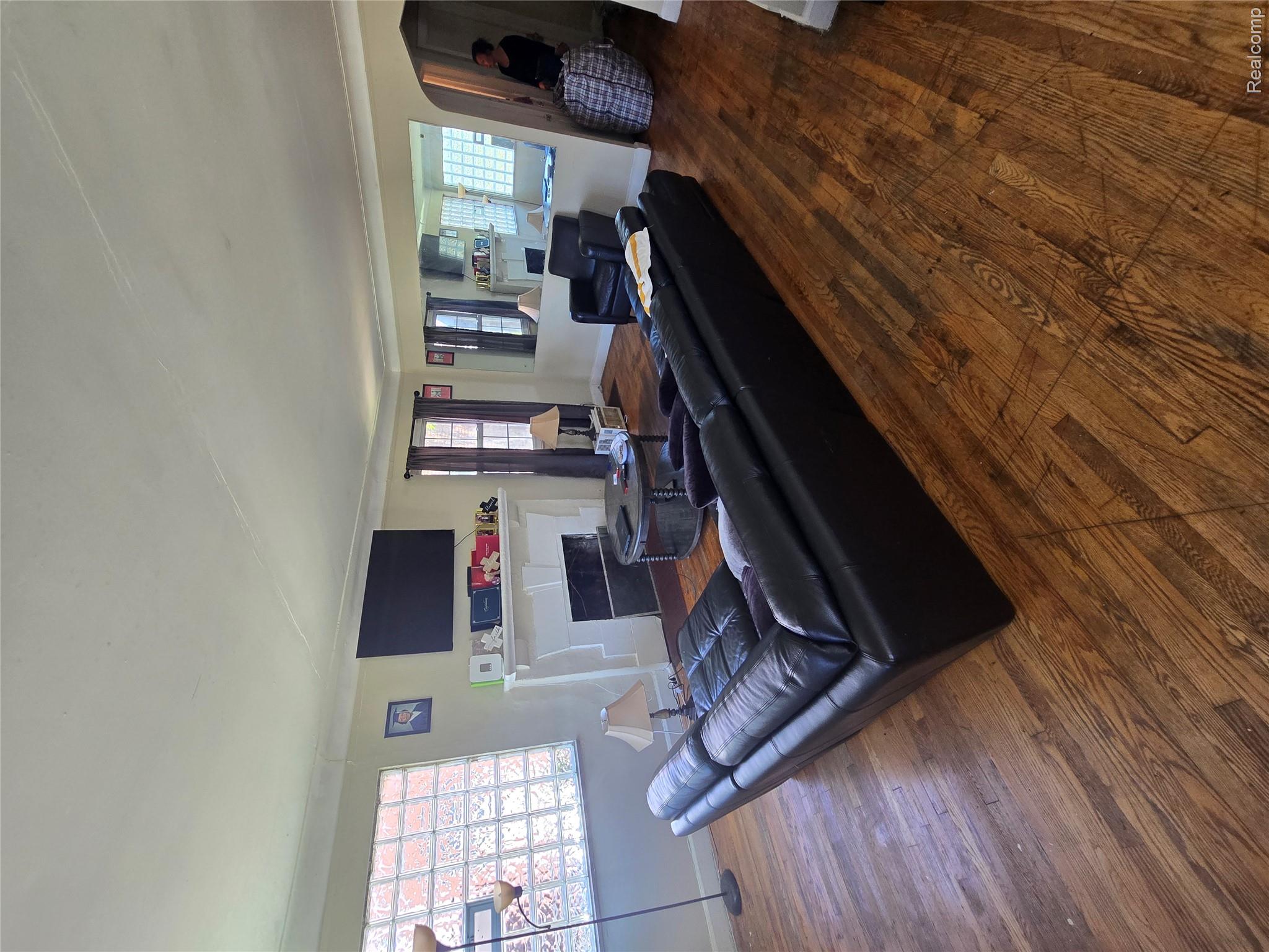 10342 Roxbury Street Detroit, MI 48224 - Photo 11 of 30 Hardwood flooring, cased openings, white crown molding, a fireplace, and glass block windows