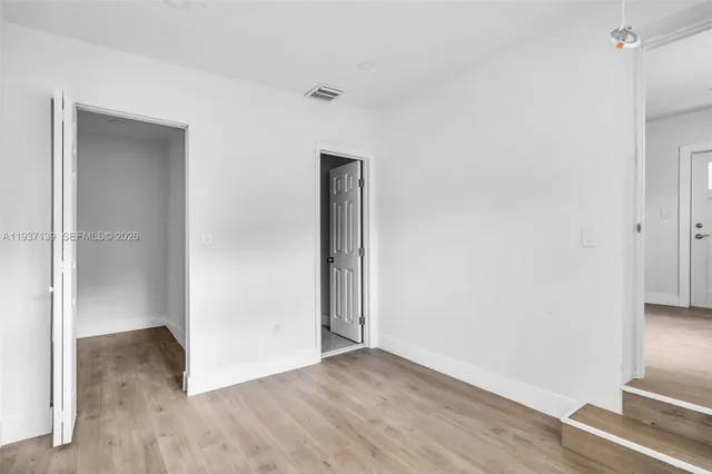 a view of an empty room with wooden floor and closet