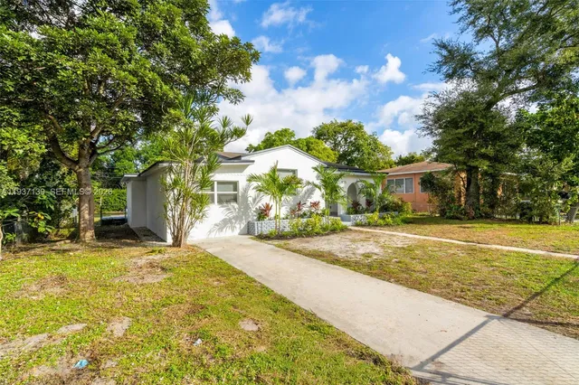 a front view of a house with a garden and trees