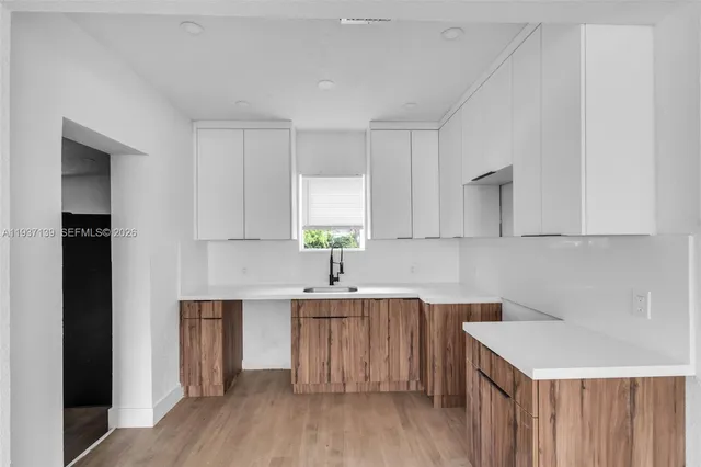 a kitchen with a sink a stove cabinets and wooden floor