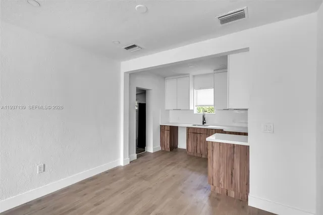 a view of a kitchen with a sink wooden cabinets and a refrigerator