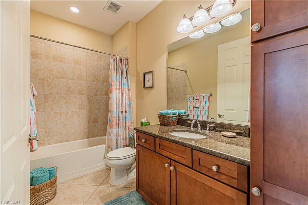 9063 Capistrano Street North, Unit 4405 Naples, FL 34113 - Photo 14 of 37 a bathroom with a granite countertop sink a toilet a mirror a shower and bathtub