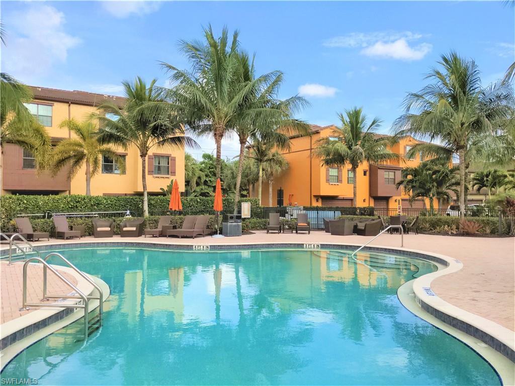 9063 Capistrano Street North, Unit 4405 Naples, FL 34113 - Photo 20 of 37 a view of a swimming pool with a lawn chairs under palm trees