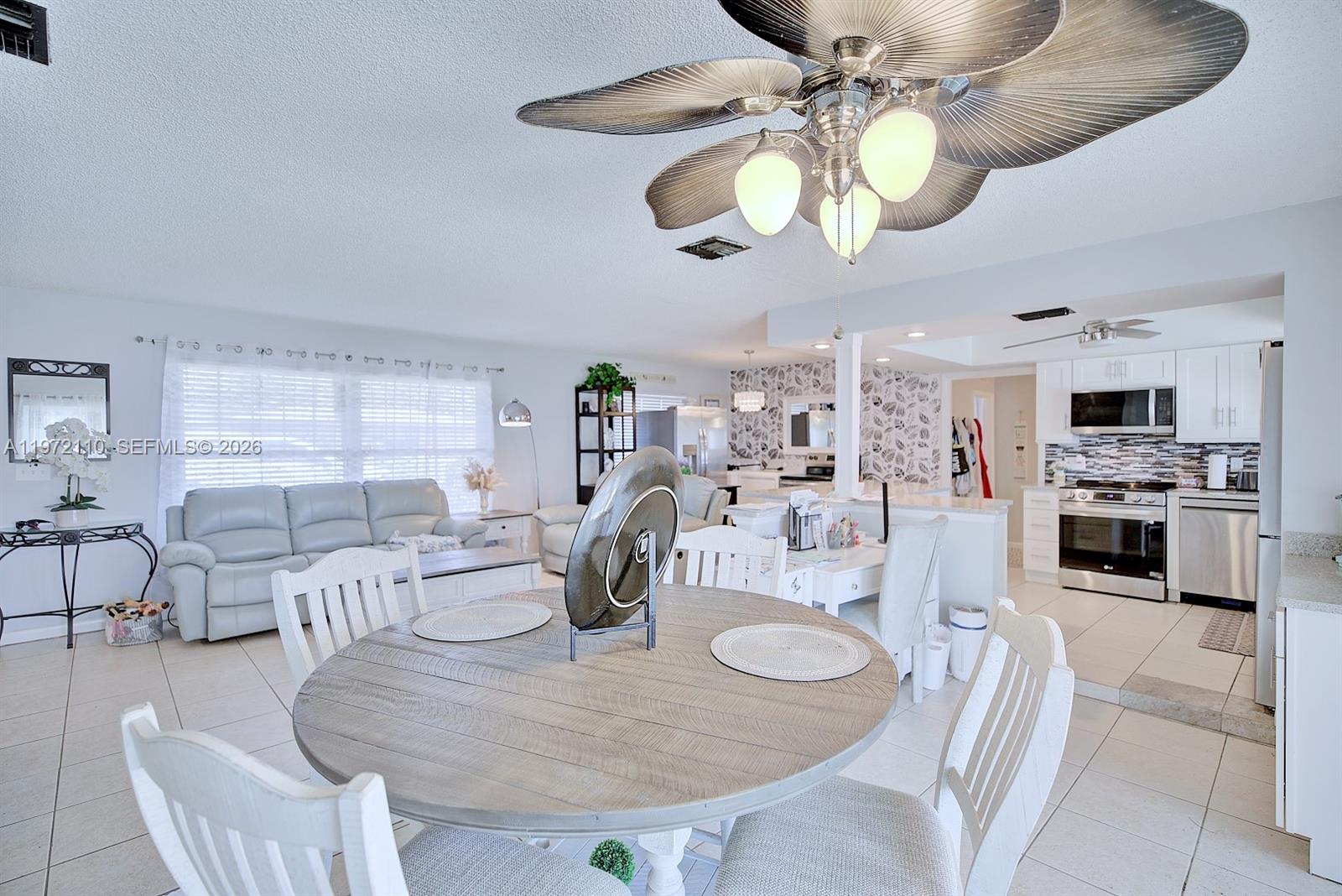 4131 Bianca Street Sebring, FL 33872 - Photo 9 of 30 a kitchen with stainless steel appliances kitchen island granite countertop a stove a sink a dining table and chairs with wooden floor