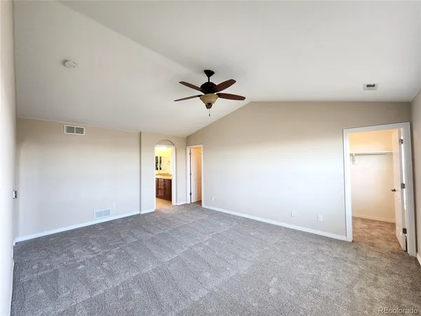 a view of an empty room with a ceiling fan and window